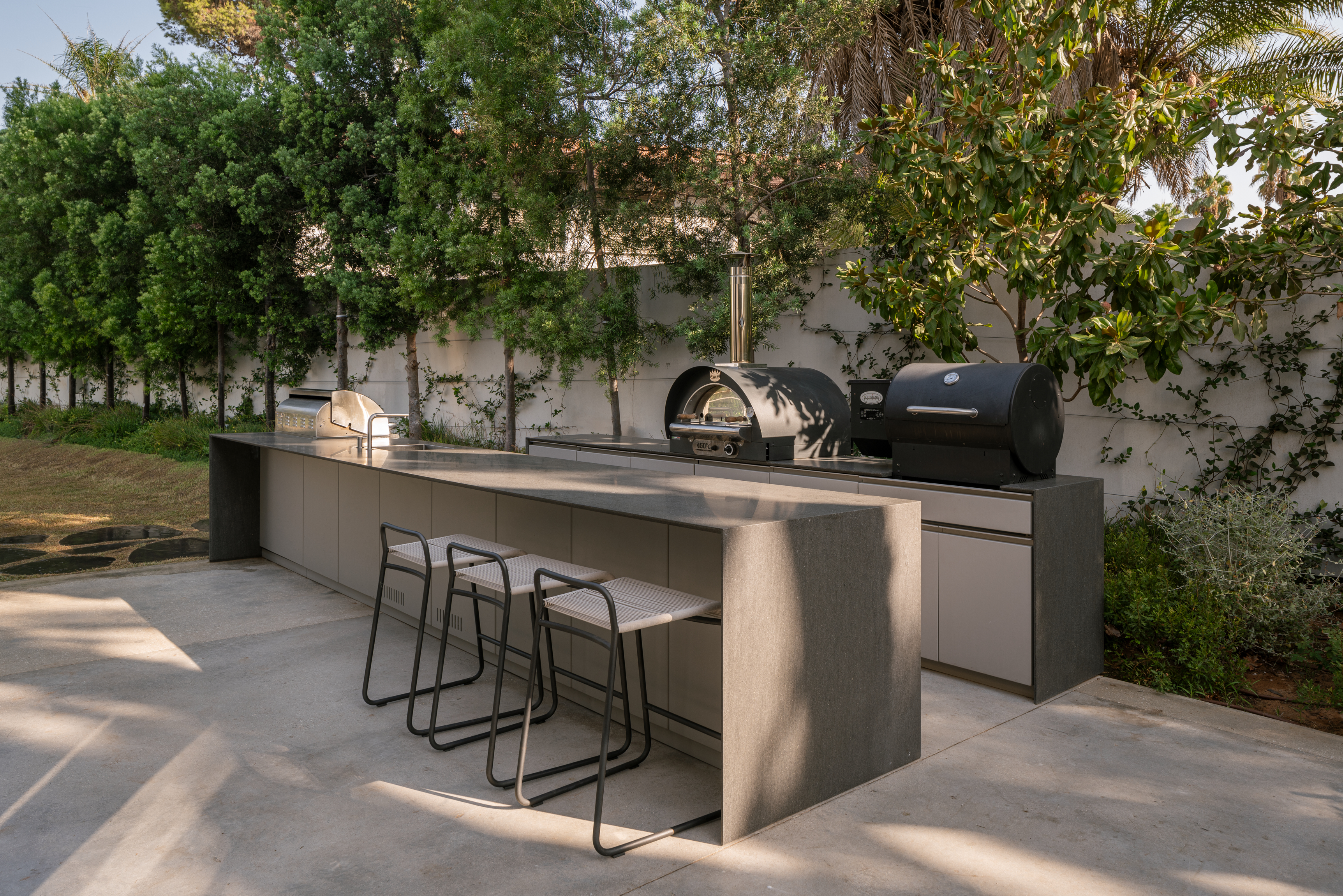 Long UNICA island with black stools, pizza oven and smoker